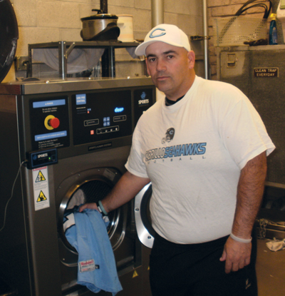 Cabrillo College equipment room manager standing next to a Sports Laundry System Washer-extractor