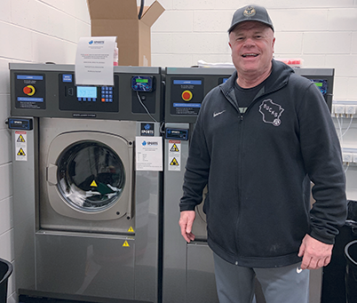 Herd Equipment Manager Mike Sergo stands in front of the Menominee Nation Arena’s new Sports Laundry System washer-extractors. They work seamlessly with ozone injection to disinfect athletic laundry